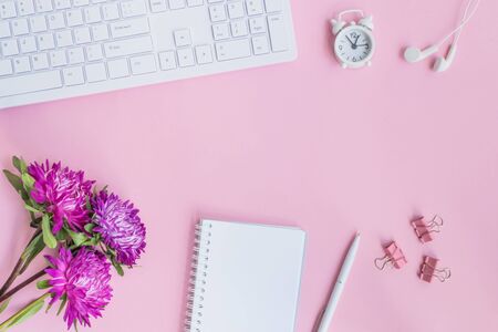 Blogger or freelancer workspace with notebook and pink flowers on pink backgroundの写真素材
