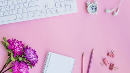 Blogger or freelancer workspace with notebook and pink flowers on pink backgroundの写真素材