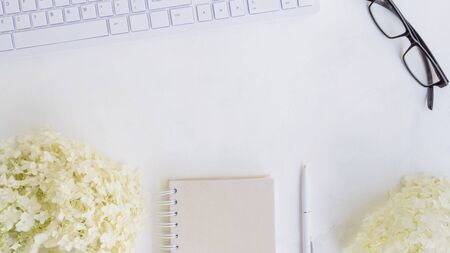 Blogger or freelancer workspace with notebook and white flower hydrangea on light backgroundの写真素材