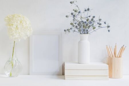 Home interior with decor elements. White frame, flowers in a vase, books and pencilsの写真素材