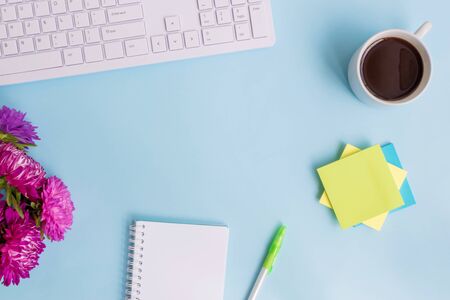 Blogger or freelancer workspace with notebook and pink flowers on blue backgroundの写真素材