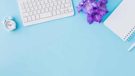 Blogger or freelancer workspace with notebook and keyboard on blue backgroundの写真素材