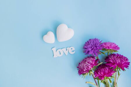 Bouquet with pink flowers and white hearts on blue background with letters loveの写真素材