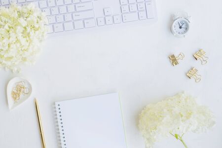 Blogger or freelancer workspace with notebook and white flower hydrangea on light backgroundの写真素材