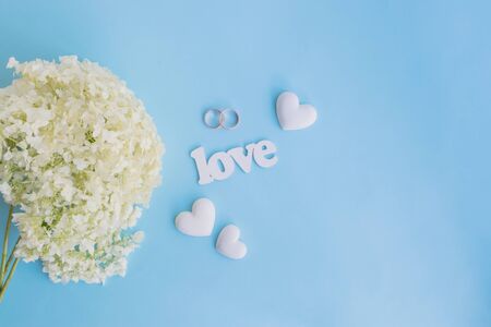 Wedding invitation with white flower hydrangea on a blue background and letters loveの写真素材
