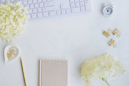 freelancer workspace with notebook and white flower hydrangea on light backgroundの写真素材