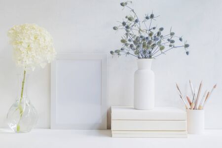 Home interior with decor elements. White frame, flowers in a vase, books and pencilsの写真素材