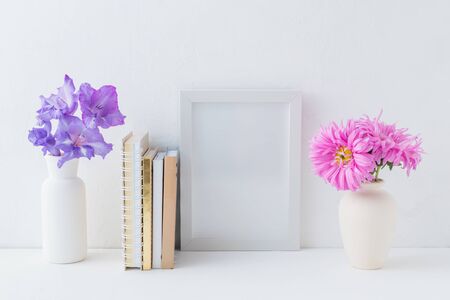 Home interior with decor elements. White frame, flowers in a vase, booksの写真素材