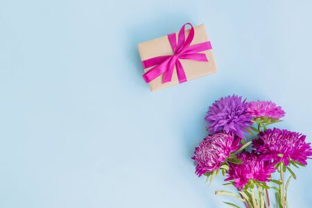 Bouquet with pink flowers with gift box on blue background empty space for your text, top viewの写真素材