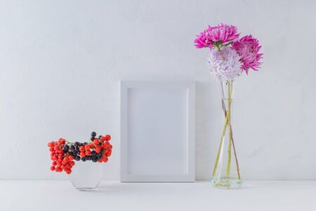 Mockup with a white frame and pink flowers in a vase on a light backgroundの写真素材