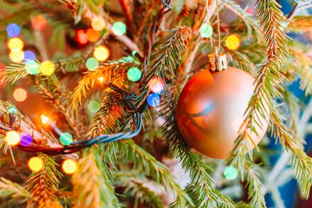 Festive background with christmas ball and garland hanging from fir branches