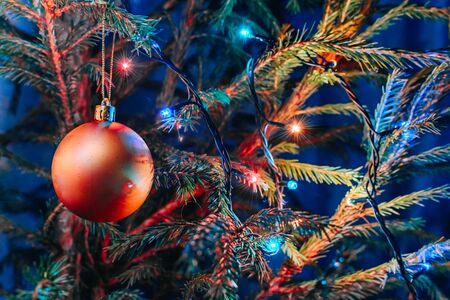 Festive background with christmas ball and garland hanging from fir branchesの写真素材