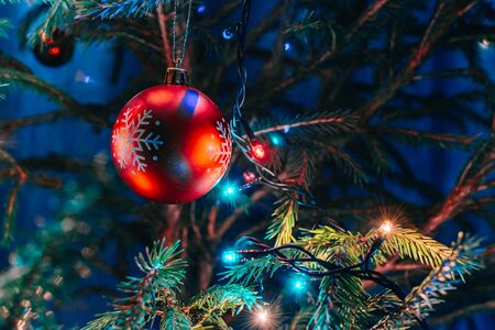 Festive background with christmas ball and garland hanging from fir branchesの写真素材