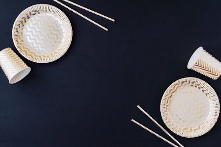 Party decoration background. Golden disposable dishes on dark wooden backgroundの写真素材