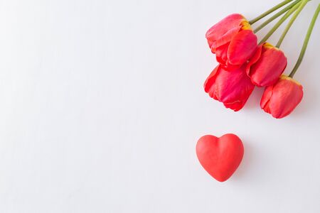 Valentines day composition with red tulips and hearts on a light background. Flat lay, top view