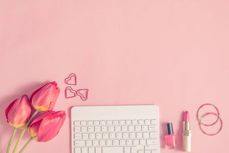 Blogger or freelancer workspace with keyboard and red tulips on pink backgroundの写真素材