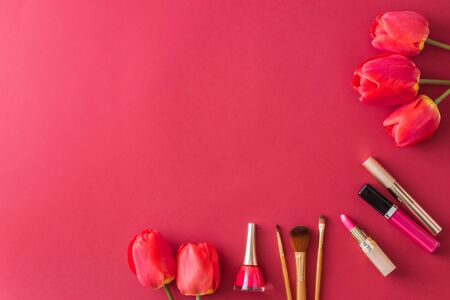 Flat lay composition with cosmetics and red tulip flowers on red tableの写真素材