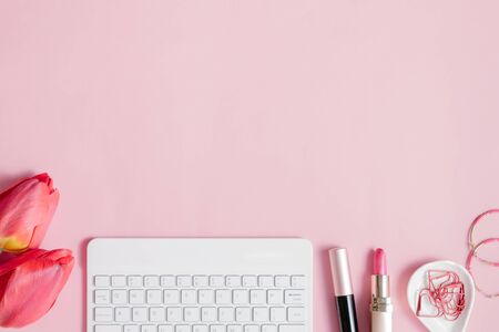 Blogger or freelancer workspace with keyboard and red tulips on pink backgroundの写真素材