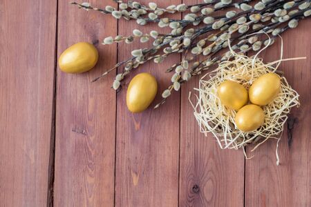 Easter festive decor with willow branches, eggs on a wooden background