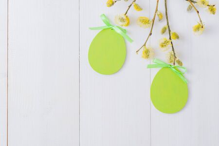 Flat lay easter composition with a willow branch and eggs on a white wooden backgroundの写真素材