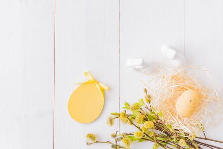 Flat lay easter composition with a willow branch and eggs on a white wooden backgroundの写真素材