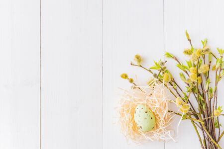Flat lay easter composition with a willow branch and eggs on a white wooden background