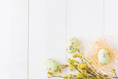 Flat lay easter composition with a willow branch and eggs on a white wooden background