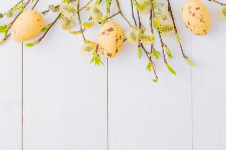 Flat lay easter composition with a willow branch and eggs on a white wooden background