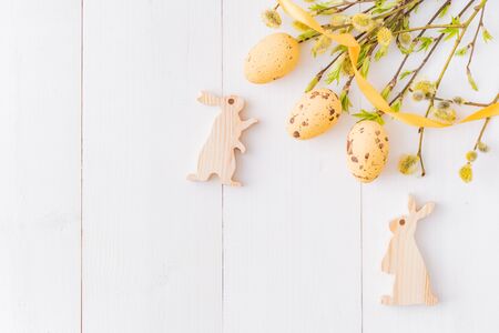 Flat lay easter composition with a willow branch and rabbit on a white wooden backgroundの写真素材