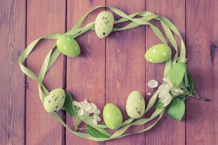 Flat lay wreath with easter eggs and white spring flowers on a wooden backgroundの写真素材
