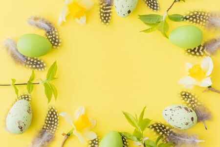 Flat lay easter composition with yellow daffodils and eggs on a yellow background