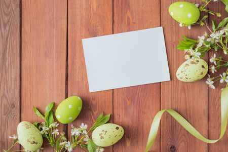 Mockup white greeting card and easter eggs with white spring flowers on a yellow background