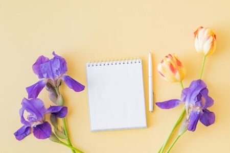 Mockup white notebook with yellow tulips and blue irises on a yellow backgroundの写真素材