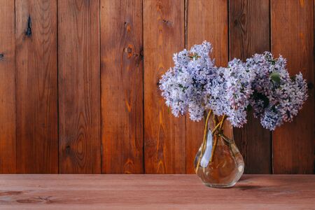Home interior with decor elements. branches of lilac in a vase on a wooden tableの写真素材