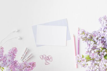 Mockup white greeting card and envelope with branches of lilac on a light backgroundの写真素材