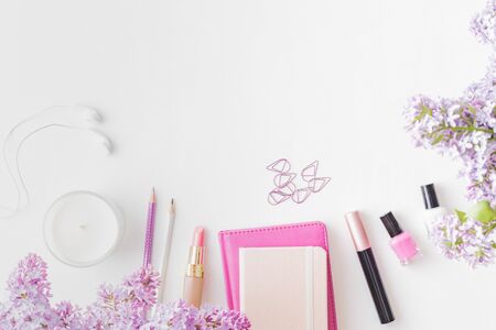 Flat lay blogger or freelancer workspace with a notebook and branches of lilac on a white table