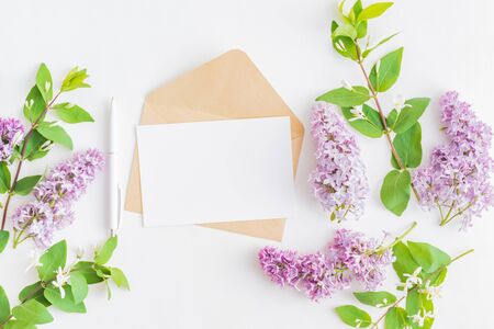 Mockup white greeting card and envelope with branches of lilac on a white backgroundの写真素材