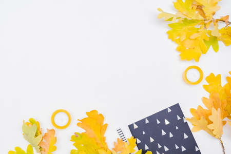 Flat lay blogger or freelancer workspace with a notebook, colorful autumn leaves on a white...