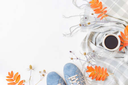 Flat lay composition with a sneakers, scarf, cup of coffee and colorful autumn leaves on a white backgroundの写真素材