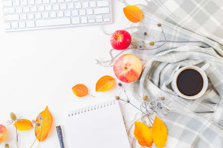 Flat lay blogger or freelancer workspace with a notebook, keyboard, scarf and colorful autumn leaves on a white backgroundの写真素材
