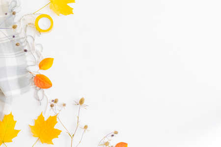 Flat lay border with a scarf and colorful autumn leaves on a white background
