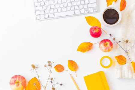 Flat lay blogger or freelancer workspace with a notebook, keyboard, sweater and colorful autumn leaves on a white backgroundの写真素材