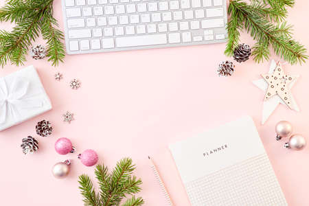 Flat lay christmas home office desk with spruce branche and keyboard, christmas decorations on a color backgroundの写真素材