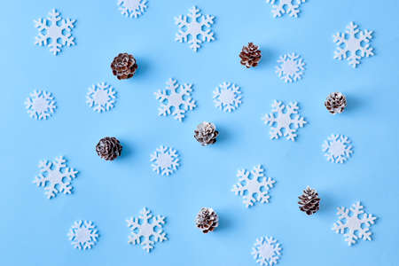 Flat lay christmas pattern with snowflakes and cones on a blue background