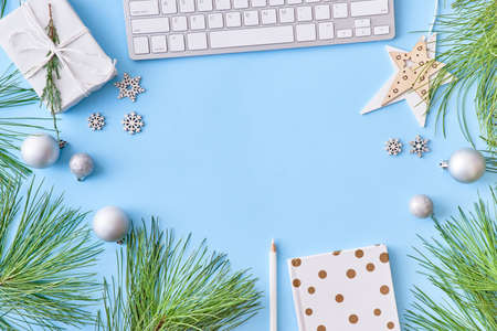 Flat lay christmas home office desk with pine branches and keyboard, christmas decorations on a blue backgroundの写真素材