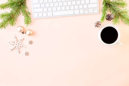 Flat lay christmas home office desk with spruce branche and keyboard, christmas decorations on a color backgroundの写真素材