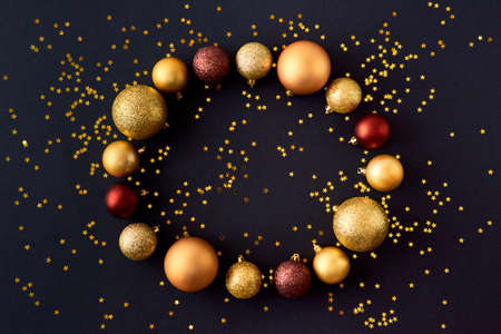 Flat lay frame with gold christmas balls and golden confetti on a dark backgroundの写真素材