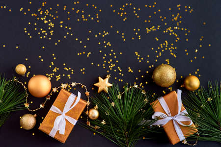 Flat lay border with gold christmas balls and gift box on a dark background