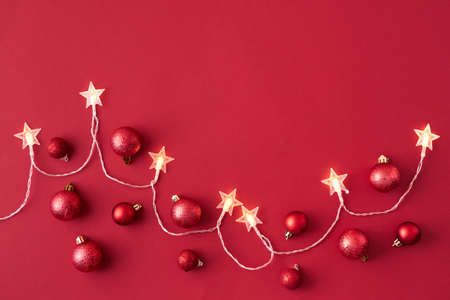 Flat lay frame with christmas garland and red christmas balls on a red background