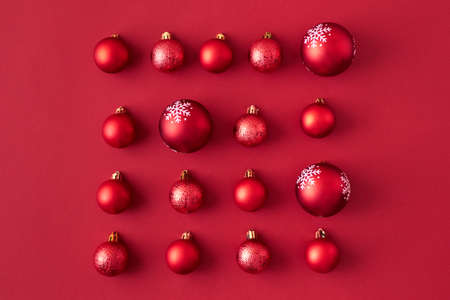 Flat lay pattern with red christmas balls on a red backgroundの写真素材